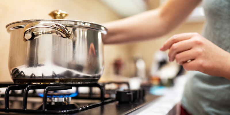 person heating a pot on a gas stove