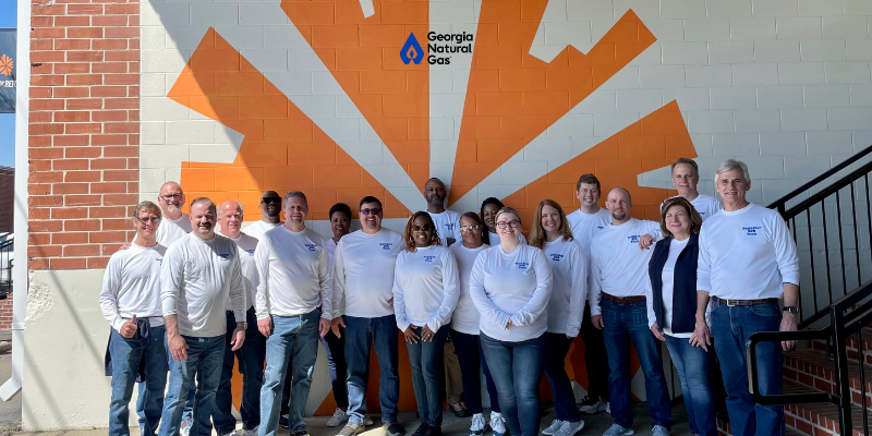 group of employees in front of orange mural