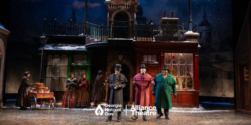 People standing in custom on a stage. GNG and Alliance Theatre logo lock up in white.