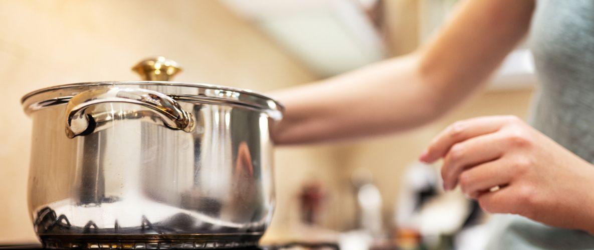 person heating a pot on a gas stove