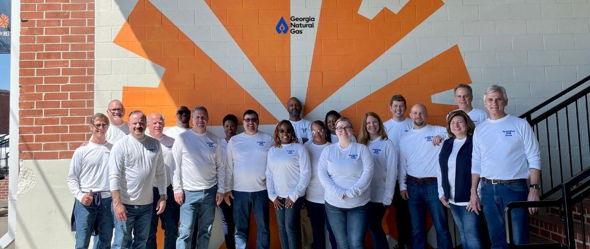 group of employees in front of orange mural